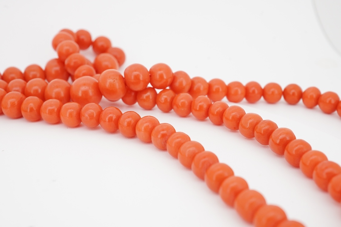 A triple strand graduated coral bead choker necklace, with a cabochon coral set white metal clasp, 38cm.